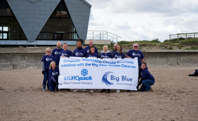 Storopack employees standing behind a banner for the organization Big Blue Ocean Cleanup on the beach