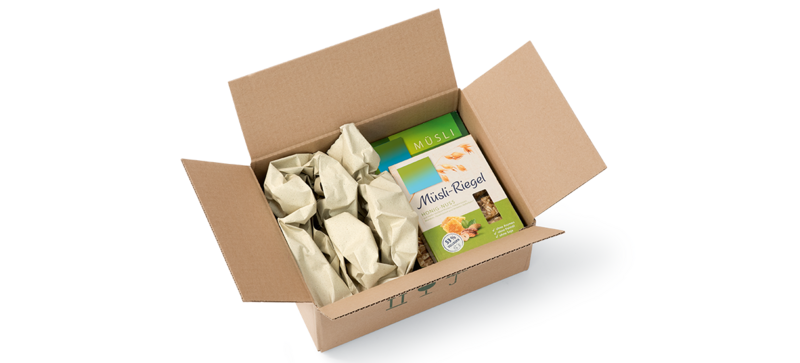 A cardboard box containing a pack of muesli and paper cushioning strips made from grass paper
