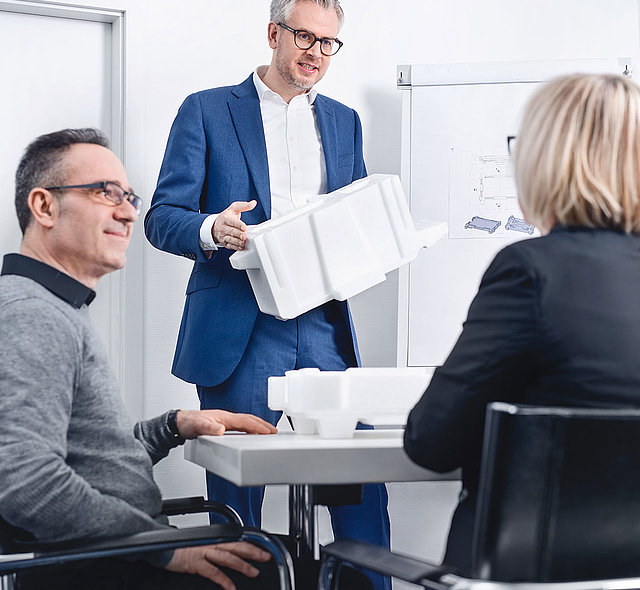 Ein Mann präsentiert zwei Kunden eine Isolierbox